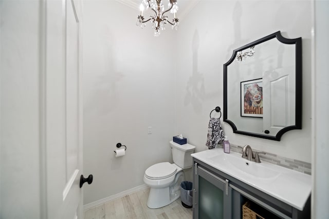 bathroom with toilet, a chandelier, vanity, wood finished floors, and backsplash