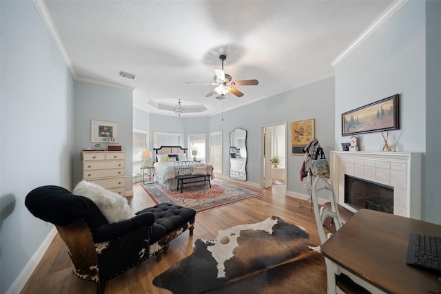 living area with crown molding, a ceiling fan, baseboards, a fireplace, and wood finished floors