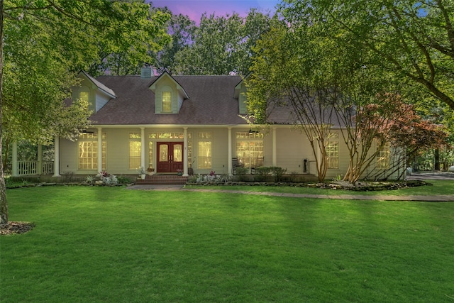 new england style home featuring french doors, a front yard, a porch, and a chimney
