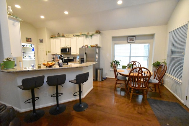 20815 Crimson Oak Trl, Humble, TX 77346 - kitchen with appliances with stainless steel finishes, lofted ceiling, dark wood-type flooring, light stone countertops, and white cabinets