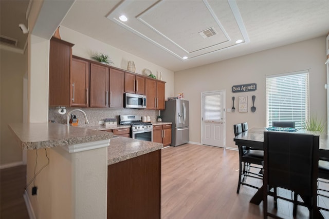 8113 E Pine Creek Bnd, Cypress, TX 77433 - kitchen featuring stainless steel appliances, brown cabinetry, recessed lighting, light wood finished floors, and backsplash