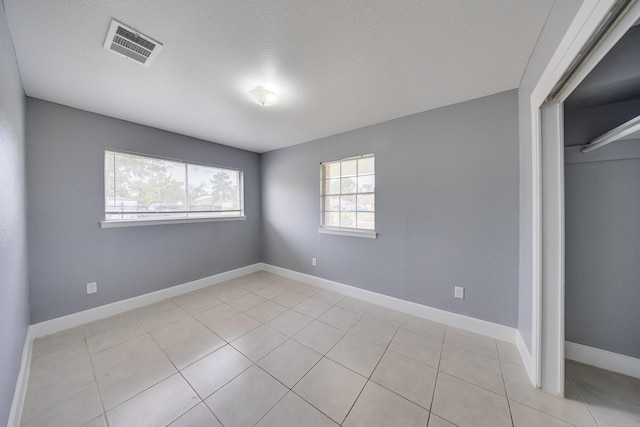 722 Dell Dale St, Channelview, TX 77530 - unfurnished bedroom featuring light tile patterned flooring, baseboards, a closet, and a textured ceiling