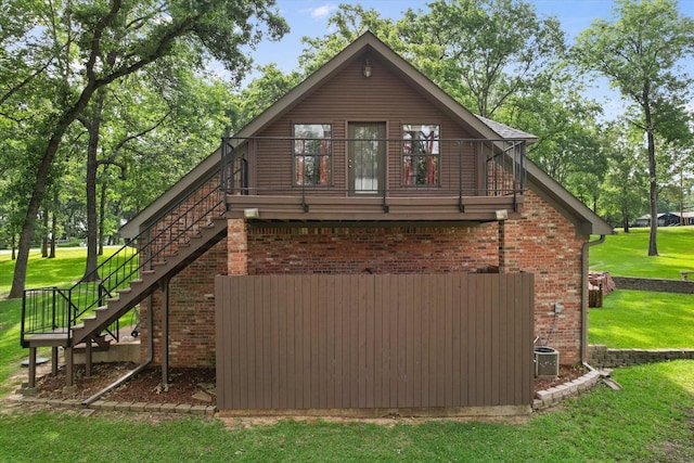 123 June Blvd, Streetman, TX 75859 - rear view of property featuring stairway, a lawn, a balcony, and brick siding