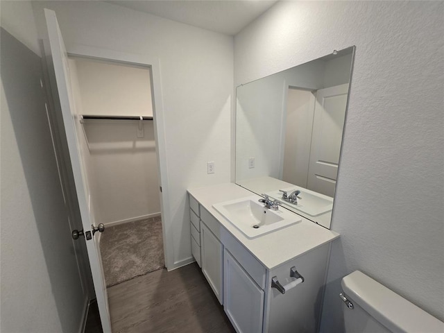 315 Brandi Dr, Wharton, TX 77488 - bathroom with wood finished floors, vanity, toilet, a textured wall, and a walk in closet