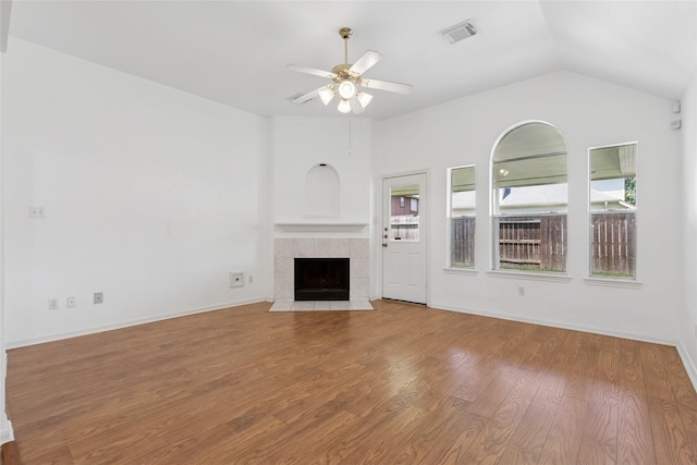 6414 Windmist Cir, Houston, TX 77084 - unfurnished living room with ceiling fan, wood finished floors, a tiled fireplace, vaulted ceiling, and baseboards