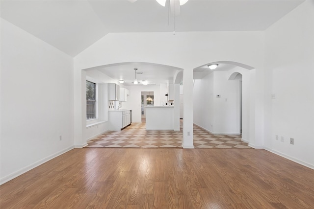 6414 Windmist Cir, Houston, TX 77084 - unfurnished living room with ceiling fan, arched walkways, light wood-style flooring, vaulted ceiling, and baseboards