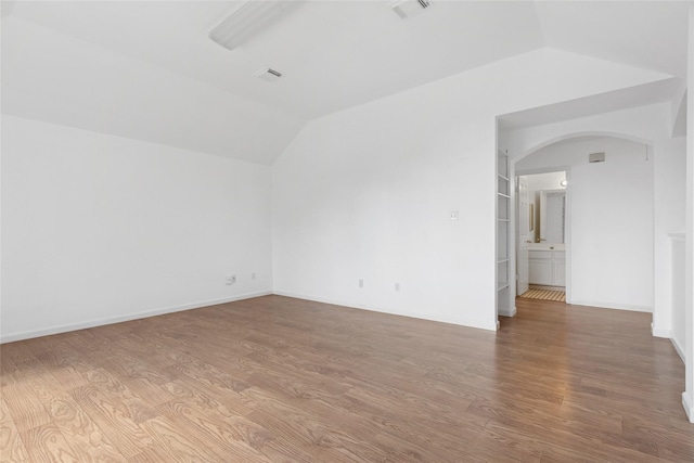 6414 Windmist Cir, Houston, TX 77084 - spare room featuring arched walkways, lofted ceiling, wood finished floors, and baseboards