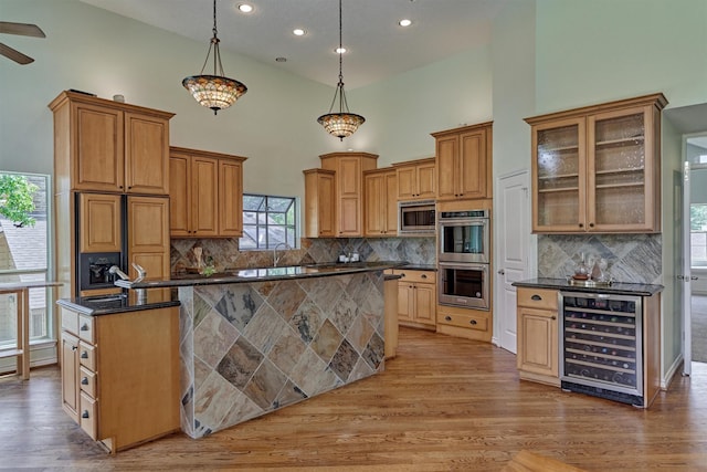 kitchen with wine cooler, appliances with stainless steel finishes, a kitchen island, recessed lighting, and light wood-style floors