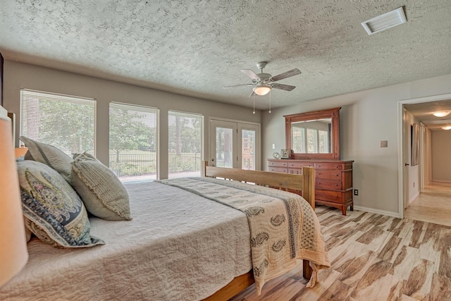 bedroom featuring access to exterior, a textured ceiling, light wood-type flooring, baseboards, and a ceiling fan