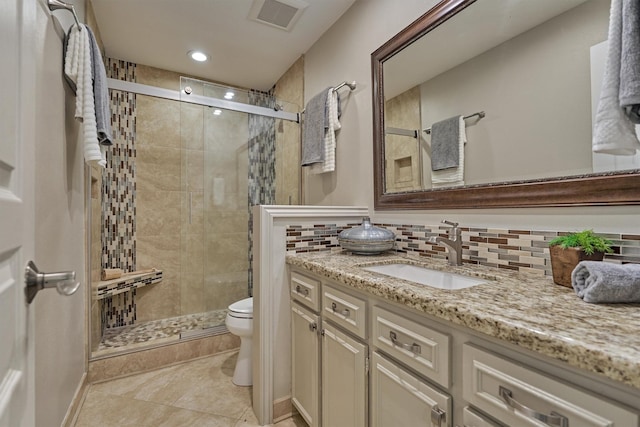 bathroom with toilet, a stall shower, vanity, tile patterned flooring, and tasteful backsplash