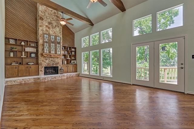 unfurnished living room featuring high vaulted ceiling, a ceiling fan, wood finished floors, a fireplace, and beamed ceiling