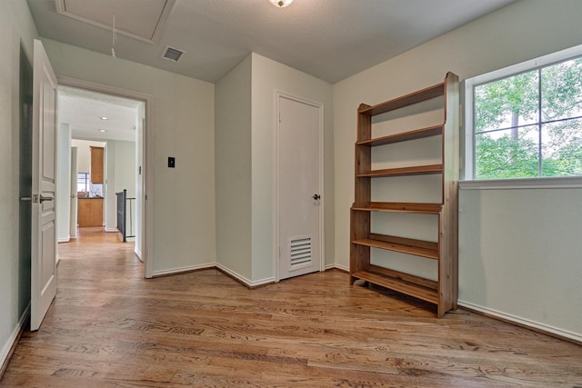 unfurnished bedroom featuring attic access, wood finished floors, and baseboards