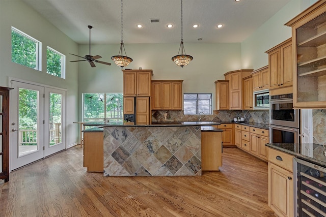 kitchen with beverage cooler, appliances with stainless steel finishes, a high ceiling, tasteful backsplash, and recessed lighting