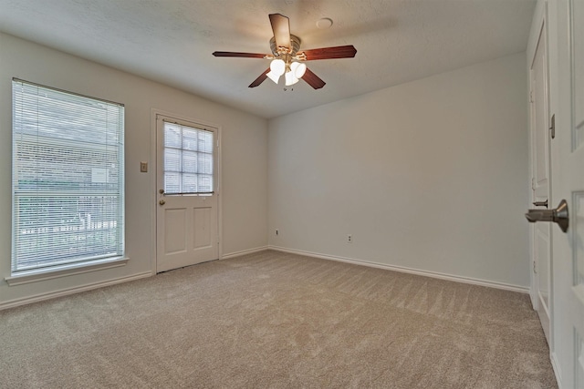 spare room featuring light carpet, baseboards, and ceiling fan