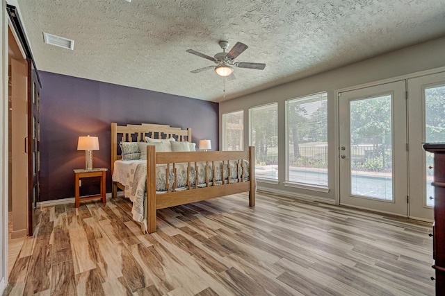 bedroom featuring access to exterior, wood finished floors, a textured ceiling, ceiling fan, and baseboards
