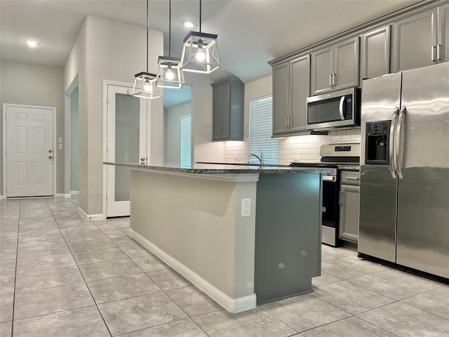 2338 Vanessa Cay Ln, La Porte, TX 77571 - kitchen with appliances with stainless steel finishes, gray cabinetry, light tile patterned flooring, backsplash, and a center island with sink