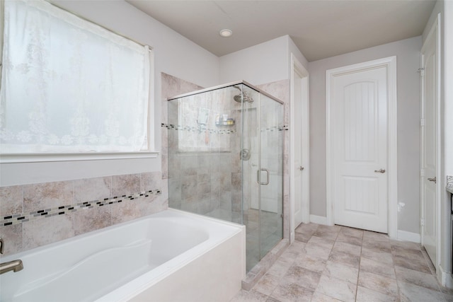 full bathroom featuring a bath, a shower stall, and baseboards