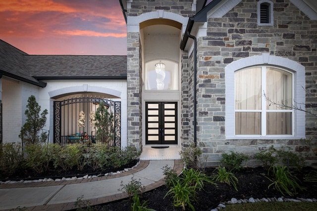 property entrance with stone siding and roof with shingles