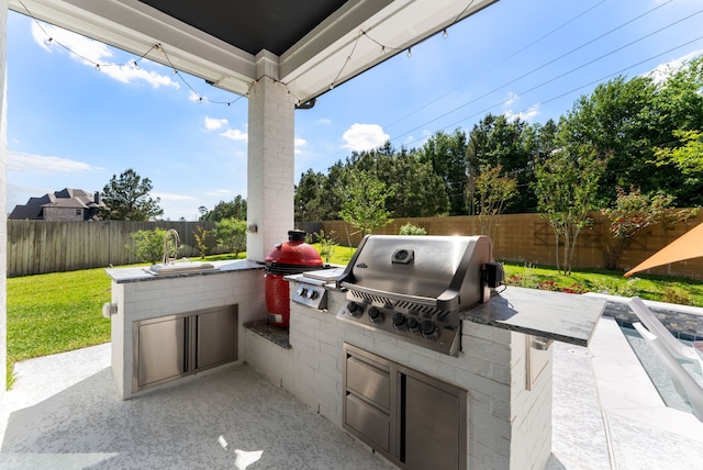 view of patio featuring area for grilling, a fenced backyard, exterior kitchen, and a sink