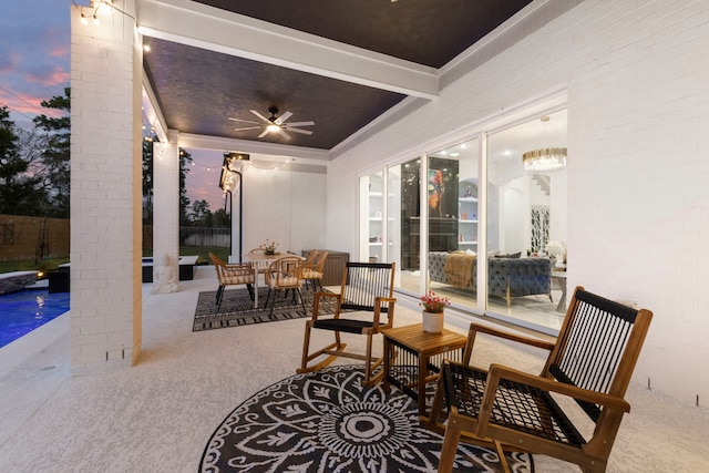 patio terrace at dusk featuring a ceiling fan and fence