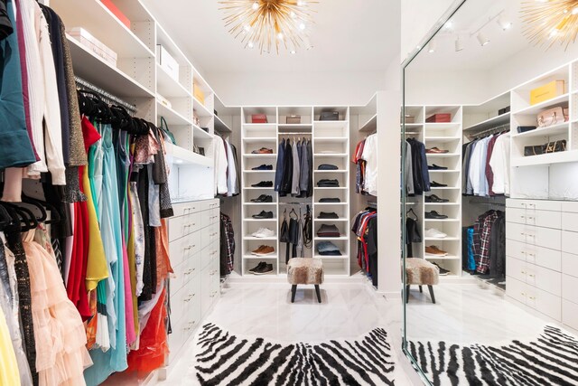 spacious closet with marble look tiles and a chandelier