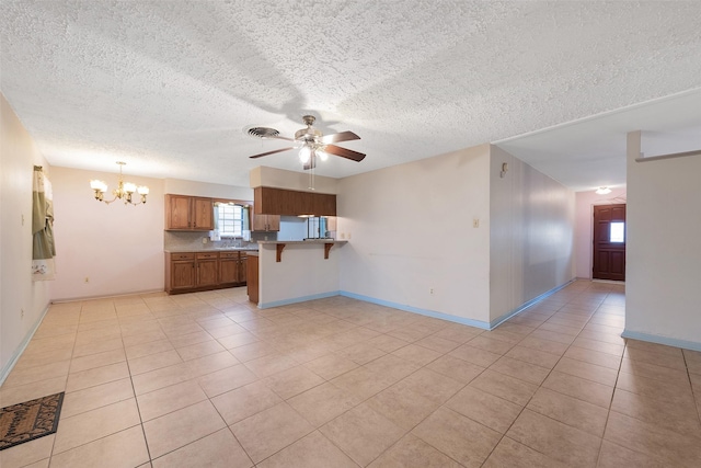 6046 Harbrook Dr, Houston, TX 77087 - unfurnished living room with a textured ceiling, a chandelier, a ceiling fan, light tile patterned floors, and baseboards