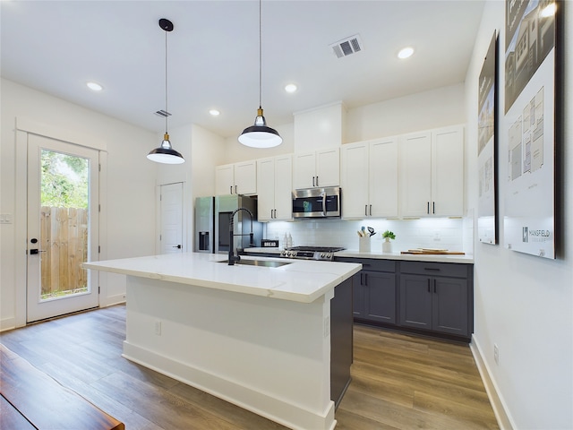 5808 Highland Sky Ln, Houston, TX 77091 - kitchen with a sink, stainless steel appliances, gray cabinetry, decorative backsplash, and a kitchen island with sink