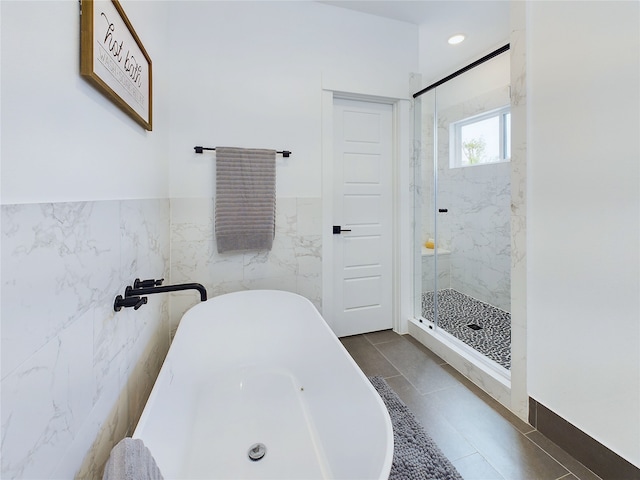 5808 Highland Sky Ln, Houston, TX 77091 - full bathroom featuring tile walls, a soaking tub, a marble finish shower, a wainscoted wall, and tile patterned floors