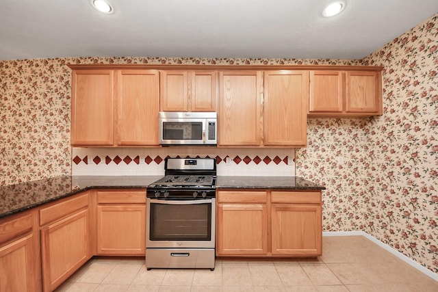 14731 Ravenscroft Way, Houston, TX 77083 - kitchen featuring stainless steel appliances, wallpapered walls, dark stone countertops, baseboards, and light tile patterned floors