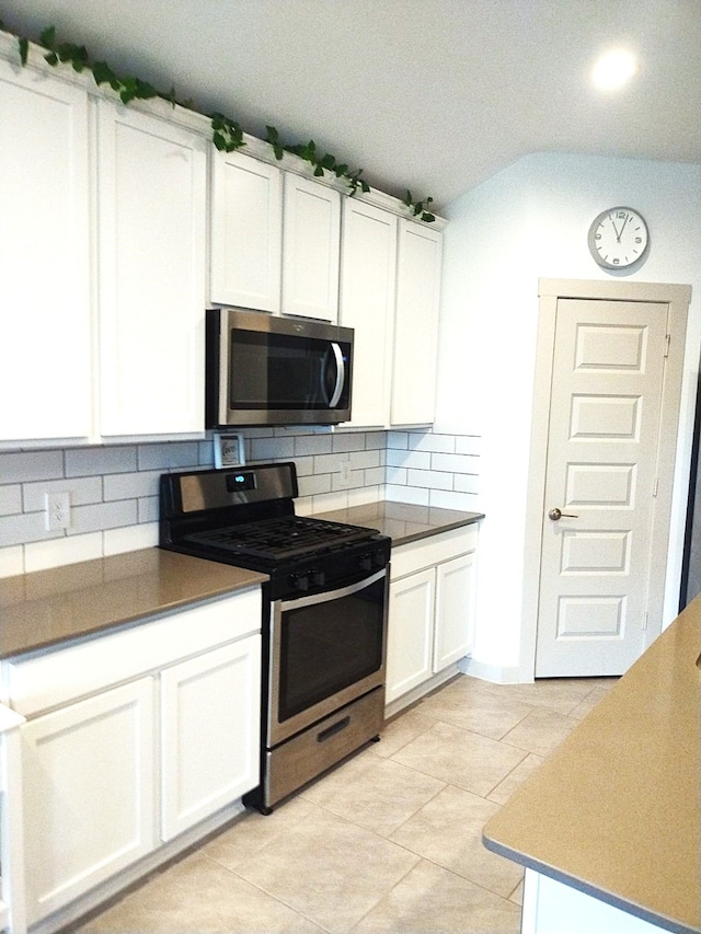 19027 Drayton Village Trce, Richmond, TX 77407 - kitchen featuring appliances with stainless steel finishes, tasteful backsplash, white cabinets, vaulted ceiling, and light tile patterned floors