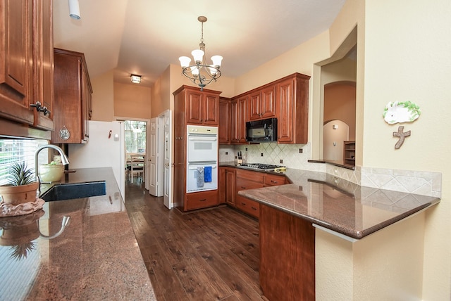 kitchen featuring black microwave, a sink, a chandelier, decorative backsplash, and dark wood-type flooring