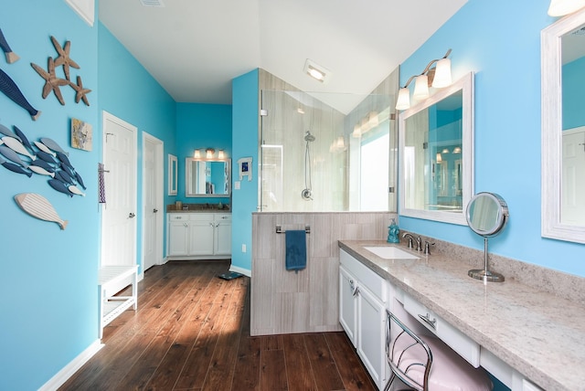 full bath featuring walk in shower, wood finished floors, and two vanities