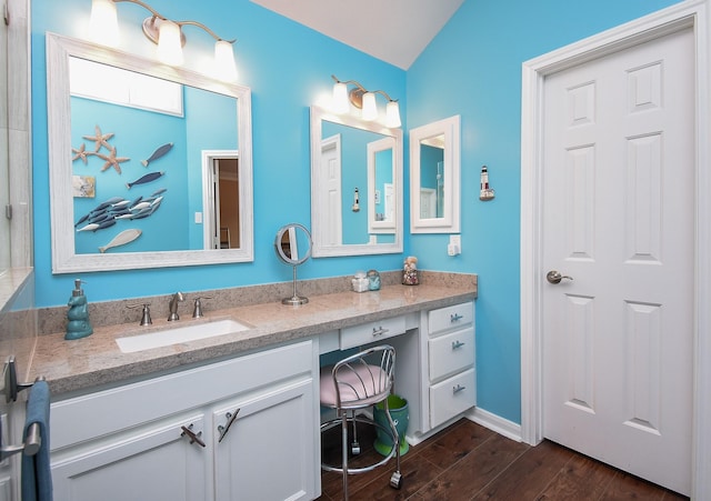 bathroom featuring vanity, wood finished floors, vaulted ceiling, and baseboards