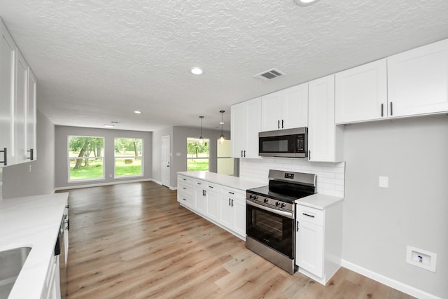 1914 Round Wind Trl, Crosby, TX 77532 - kitchen with stainless steel appliances, open floor plan, light countertops, light wood-style floors, and decorative backsplash