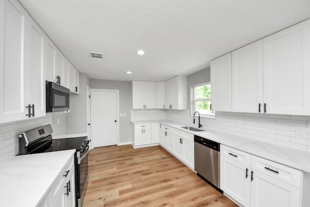1914 Round Wind Trl, Crosby, TX 77532 - kitchen with stainless steel appliances, a sink, recessed lighting, decorative backsplash, and white cabinetry