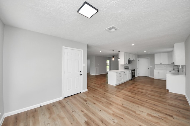 1914 Round Wind Trl, Crosby, TX 77532 - unfurnished living room with a sink, recessed lighting, light wood-type flooring, baseboards, and a textured ceiling