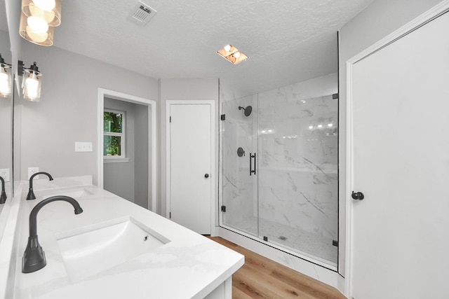 1914 Round Wind Trl, Crosby, TX 77532 - full bathroom with wood finished floors, a marble finish shower, double vanity, and a textured ceiling