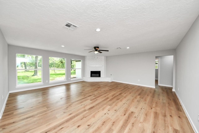 1914 Round Wind Trl, Crosby, TX 77532 - unfurnished living room with light wood-style floors, a ceiling fan, baseboards, a fireplace, and a textured ceiling