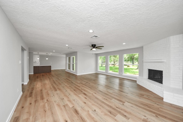 1914 Round Wind Trl, Crosby, TX 77532 - unfurnished living room with a fireplace, light wood finished floors, a textured ceiling, a ceiling fan, and baseboards