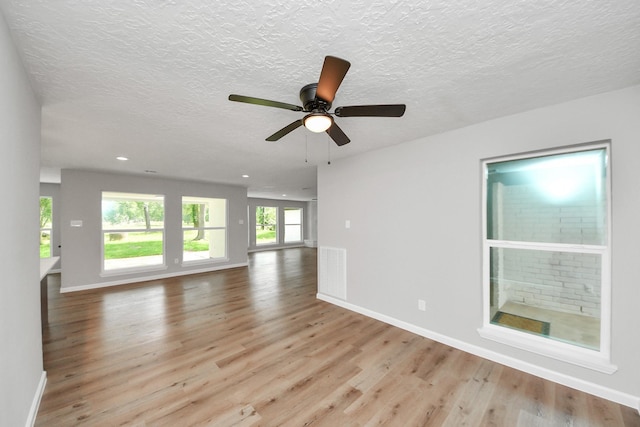 1914 Round Wind Trl, Crosby, TX 77532 - unfurnished living room featuring light wood-type flooring, a ceiling fan, baseboards, a textured ceiling, and recessed lighting