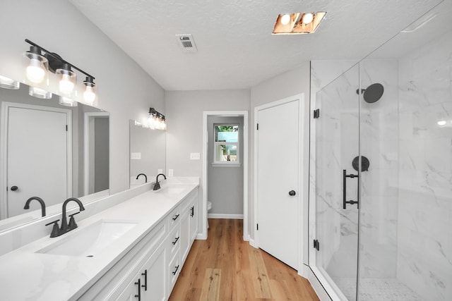 1914 Round Wind Trl, Crosby, TX 77532 - bathroom featuring wood finished floors, a marble finish shower, toilet, double vanity, and a textured ceiling