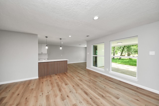 1914 Round Wind Trl, Crosby, TX 77532 - unfurnished living room with baseboards, light wood-style flooring, recessed lighting, and a textured ceiling