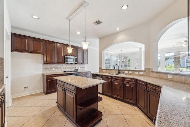 kitchen featuring a sink, stainless steel appliances, decorative backsplash, light tile patterned floors, and light stone counters