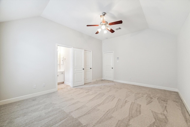unfurnished bedroom with vaulted ceiling, light carpet, ensuite bathroom, baseboards, and a ceiling fan