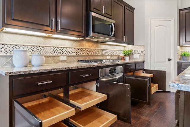 1830 Britton Key Ln, Spring, TX 77386 - kitchen with stainless steel appliances, dark brown cabinetry, dark wood-style flooring, and light stone countertops