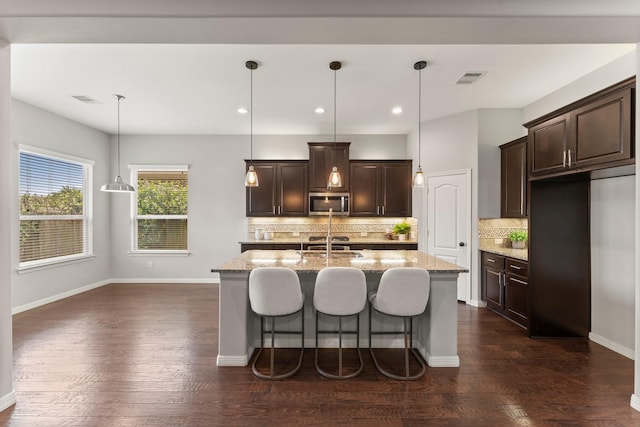 1830 Britton Key Ln, Spring, TX 77386 - kitchen with stainless steel microwave, light stone countertops, dark brown cabinets, decorative backsplash, and recessed lighting