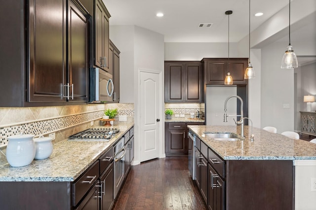 1830 Britton Key Ln, Spring, TX 77386 - kitchen with appliances with stainless steel finishes, a sink, dark brown cabinetry, dark wood-style floors, and light stone countertops
