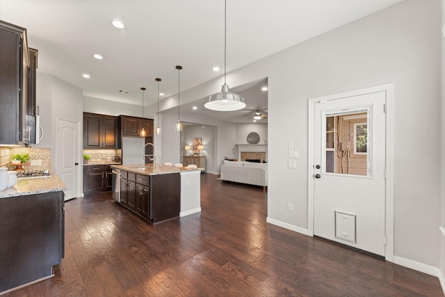 1830 Britton Key Ln, Spring, TX 77386 - kitchen with dark brown cabinets, ceiling fan, open floor plan, dark wood-style floors, and tasteful backsplash
