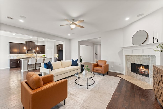 1830 Britton Key Ln, Spring, TX 77386 - living room featuring light wood-type flooring, a ceiling fan, baseboards, a tile fireplace, and recessed lighting