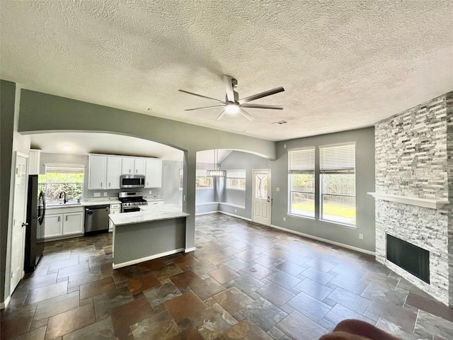3209 Crimson Coast Dr, League City, TX 77573 - kitchen featuring appliances with stainless steel finishes, ceiling fan, open floor plan, light countertops, and a stone fireplace
